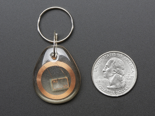 Clear keychain fob with copper coil inside, next to quarter