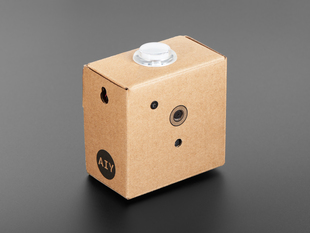 Angled shot of assembled cardboard cube with camera and white button.