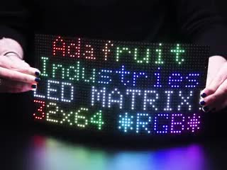 Two hands flexing a powered on 64x32 Flexible RGB LED Matrix - 5mm Pitch. 