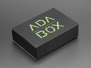 Angled shot of a black box with Green/Yellow "ADABOX" texted logo.