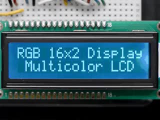 LCD wired on breadboard with backlight changing color with text displayed: "RGB 16x2 Display Mulitcolor LCD"