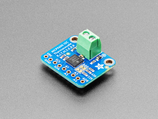 Angled shot of a square, blue, thermocouple amplifier with a green terminal block.