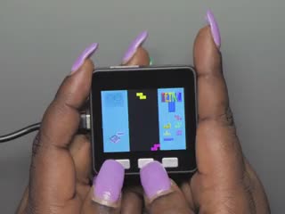 Purple polished hands playing a tetris game on a M5Stack Basic Core IoT Development Kit. 