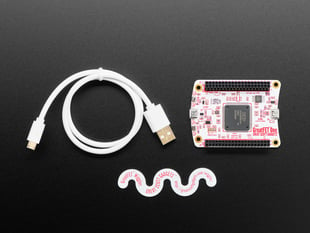 Top view of white dev board, white USB cable, and snake-shaped sticker.