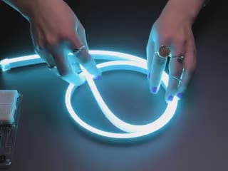 Two hands repeatedly bending and manipulating lit-up flexible silicone tubing.