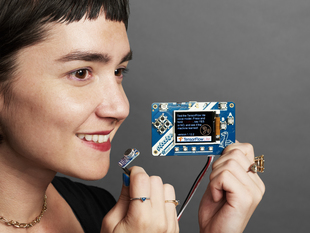Female holding an a assembled TensorFlow Lite for Microcontrollers Kit.