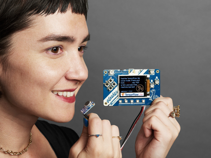 Female holding an a assembled TensorFlow Lite for Microcontrollers Kit.