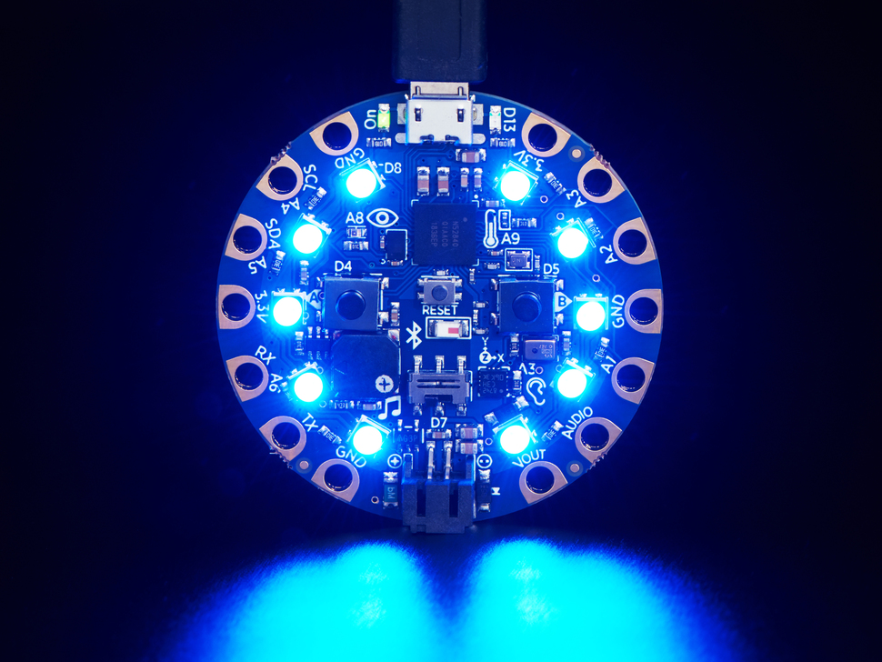 Top view of Circuit Playground Bluefruit glowing blue LEDs.