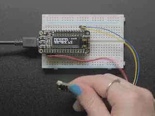 Video of a white hand moving a Adafruit LSM303AGR Accelerometer Magnetometer around and a OLED connected to a white breadboard. 