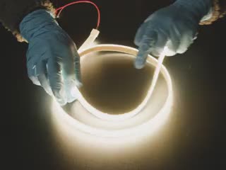 Two hands repeatedly bending and manipulating lit-up flexible warm white LED strip