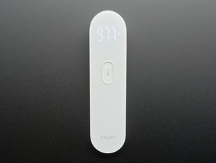 White no touch thermometer shown laying flat and displaying a temperature