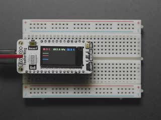 Pimoroni Enviro + FeatherWing connected to a white breadboard. Display showing sensor readings.