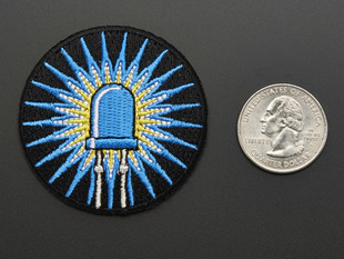Circular embroidered badge of blue LED with rays of light on black background