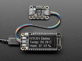 Top view of humidity breakout above an OLED display FeatherWing. The OLED display reads: "HTU31 Demo Temp: 24.19ºC Hum: 37.13%"
