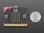 Top down view of a BBC micro:bit v2 next to US quarter for scale. 