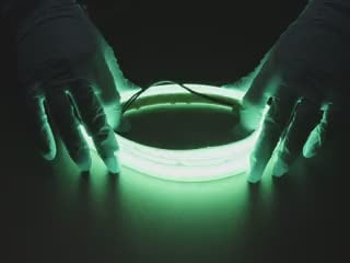Two hands repeatedly bending and manipulating lit-up flexible green LED strip