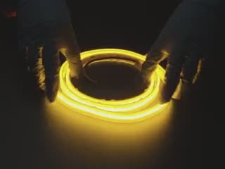 Two hands repeatedly bending and manipulating lit-up flexible yellow LED strip