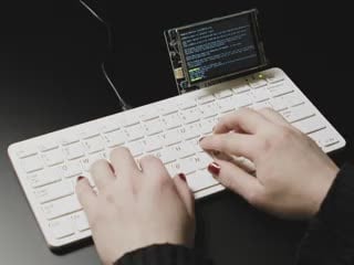 Video of a person typing code on a Pi 400 keyboard. A PiTFT display is connected to the keyboard, and a heart wallpaper appears on the TFT.