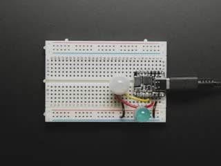 Topdown video of 3-pin PIR sensor assembled onto a breadboard. A hand passes over the sensor, and a blue LED to light up.