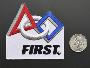 Embroidered badge with the word  FIRST in black on white background, with red triangle and blue square shapes. 