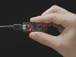 Video of hand holding an ItsyBitsy PCB. An on-board LED glows rainbow colors.