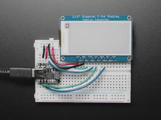 Video of a 2.13" tri-color eInk display assembled on a breadboard with jumper wires and a QT Py. Friendly snake in white-and-red, Blinka, appears on the display.