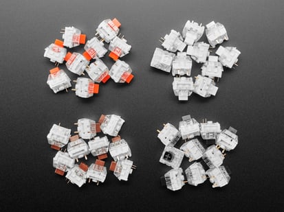 Top down view of four piles of Kailh key switches in Red, Black, Brown, and Black variations.