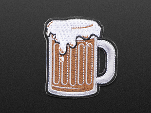 Embroidered badge in the shape of a glass handled mug. Mug is filled with brown root beer and topped with white foam, badge is edged in black.  