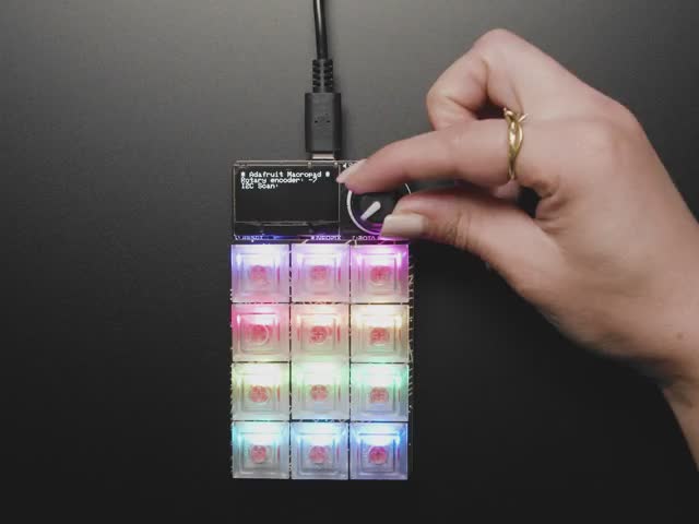 Video of a hand playing with a rainbow-glowing keypad.