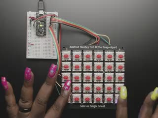 Top view video of a Black woman's hands pressing the key switches on to emit rainbow colors from the NeoPixels.
