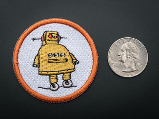 Circular embroidered badge with yellow Instructables robot on white background with orange trim. Shown next to a quarter for scale. 