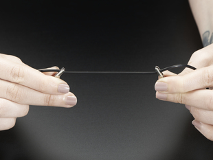 Image of a set of hands holding Conductive Rubber Cord Stretch Sensor with a set of clips.
