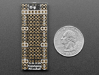 Overhead shot of bottom of long, skinny prototyping breakout board next to US quarter for scale.