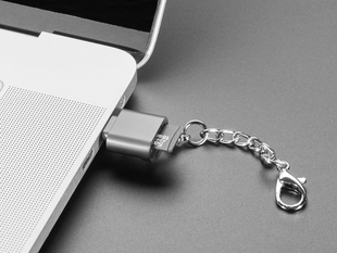 Angled shot of a microSD card reader with a key chain plugged into a laptop port.