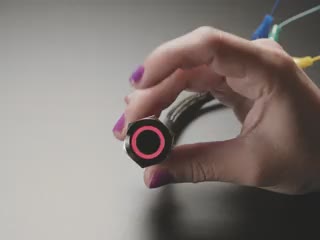 Video of a white hand pressing a metal pushbutton with a glowing rainbow LED ring.