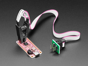 probe clip with cable attached to a SOIC chip on a pink PCB.