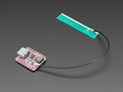 Angled shot of purple square-shaped microcontroller with a uFL antenna attached.