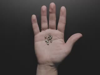 Video of a white hand holding ten wireless LED inductors in the palm of their hand. A small inductive coil is placed over the LEDs which light up blue.