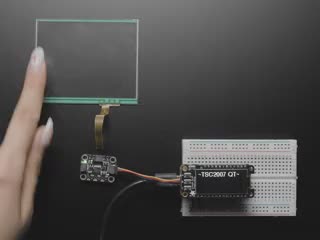 Video of a mushroom-manicured finger pressing a clear touchscreen display. The x-axis and y-axis dimensions are displayed on the connected monochrome OLED display breakout board.
