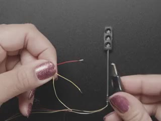 Video of a sparkly manicured finger connecting wires to make a miniature traffic light light up.
