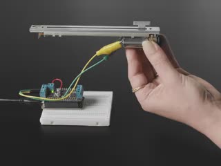 Video of a motorized slide potentiometer sliding back and forth. A white finger pushes the knob to the middle of the track, and it resumes sliding back and forth.