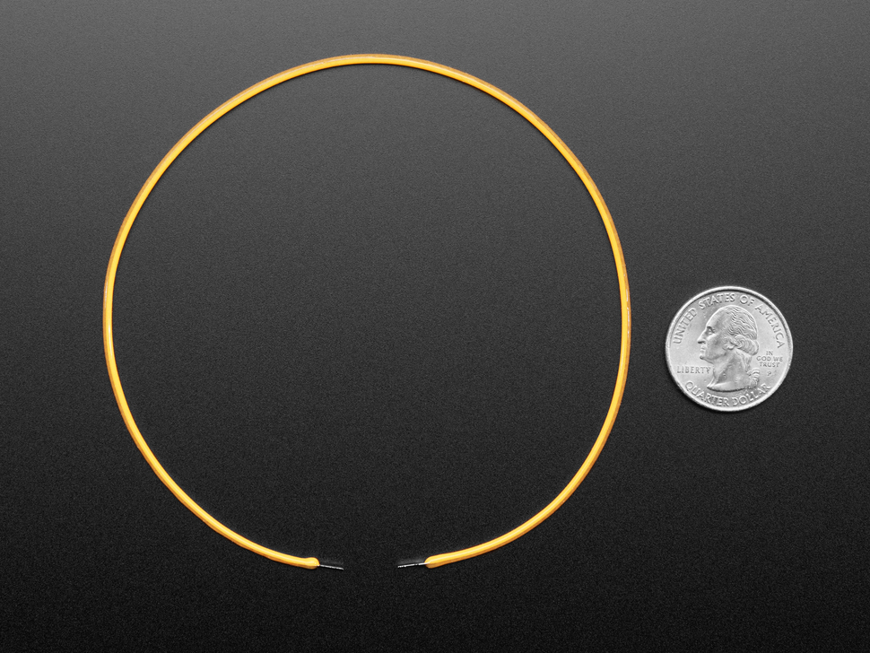 Angled shot of 300mm long lime warm white LED filament shaped in a circle next to US quarter for scale.