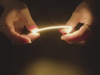 Video of a pair of white hands coiling and playing with a 130mm long warm white LED filament.