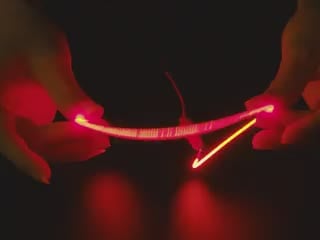 Video of a pair of white hands coiling and playing with a 300mm long red LED filament.