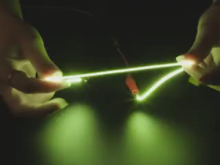 Video of a pair of white hands coiling and playing with a 300mm long green LED filament.