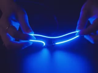 Close-up video of a pair of white hands coiling and playing with a 300mm long blue LED filament.