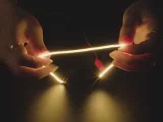 Video of a pair of white hands coiling and playing with a 300mm long yellow LED filament.