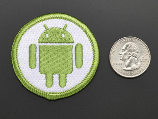 Circular embroidered badge with Android's green robot on white background with green trim. Shown next to a quarter for scale. 