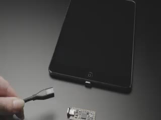 Video of a black woven magnetic USB cable being used to power on a tablet and a small, rectangular microcontroller.