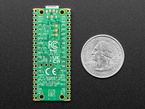 Bottom of a green microcontroller with castellated pads lain vertically next to a US quarter for scale.